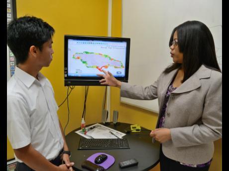 Dr Ava Maxam (right), deputy director of the Mona GeoInformatics Institute, explains a map to Dr Kioshi Mishiro from Japan, at the Mona GeoInformatics Institute's offices in St Andrew.